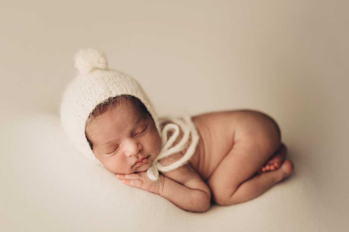 newborn baby boy laying on the white fabric