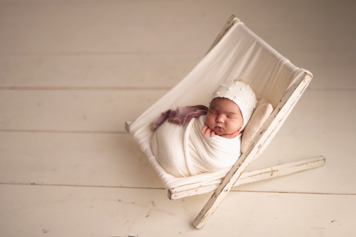 Newborn baby girl in the stool prop