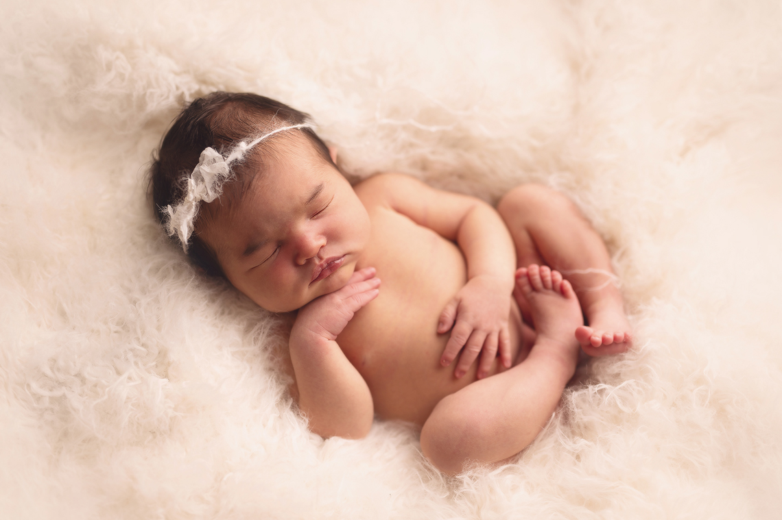 Newborn baby girl sleeping on the white fur