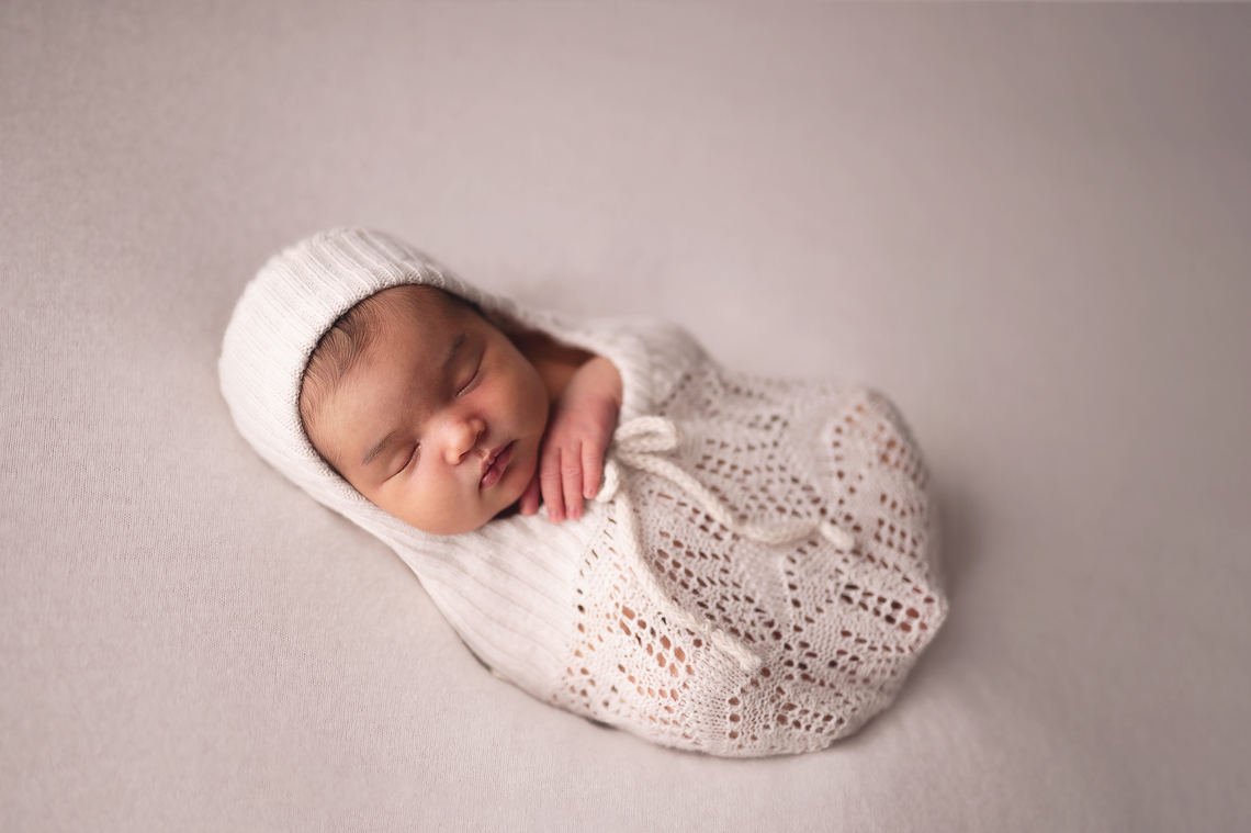 baby girl wrapped laying on white backdrop