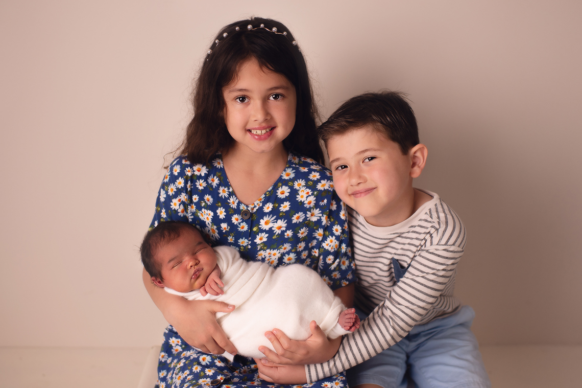 brother and sister holding a newborn baby