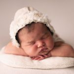 newborn baby girl in white hand made hat sleeping on the pillow