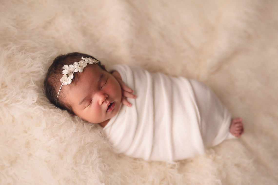 newborn baby girl wrapped in white fur
