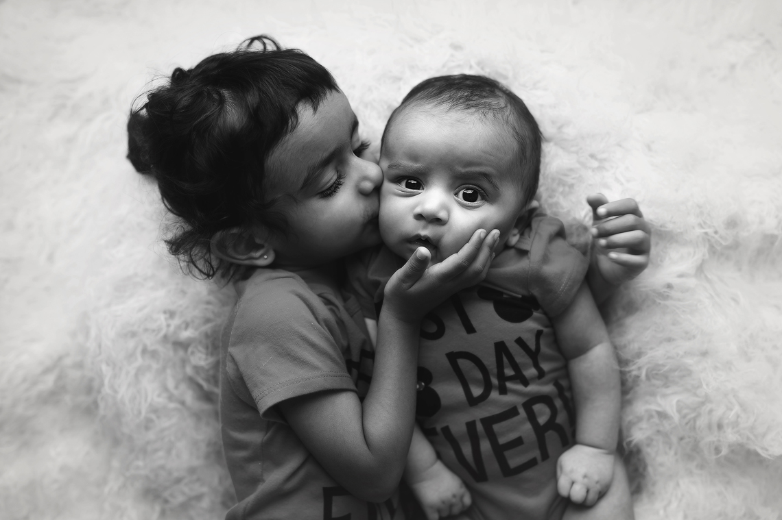 sister kissing baby brother photo