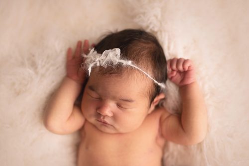 новорожденный ребенок девочка спит на белом мехе