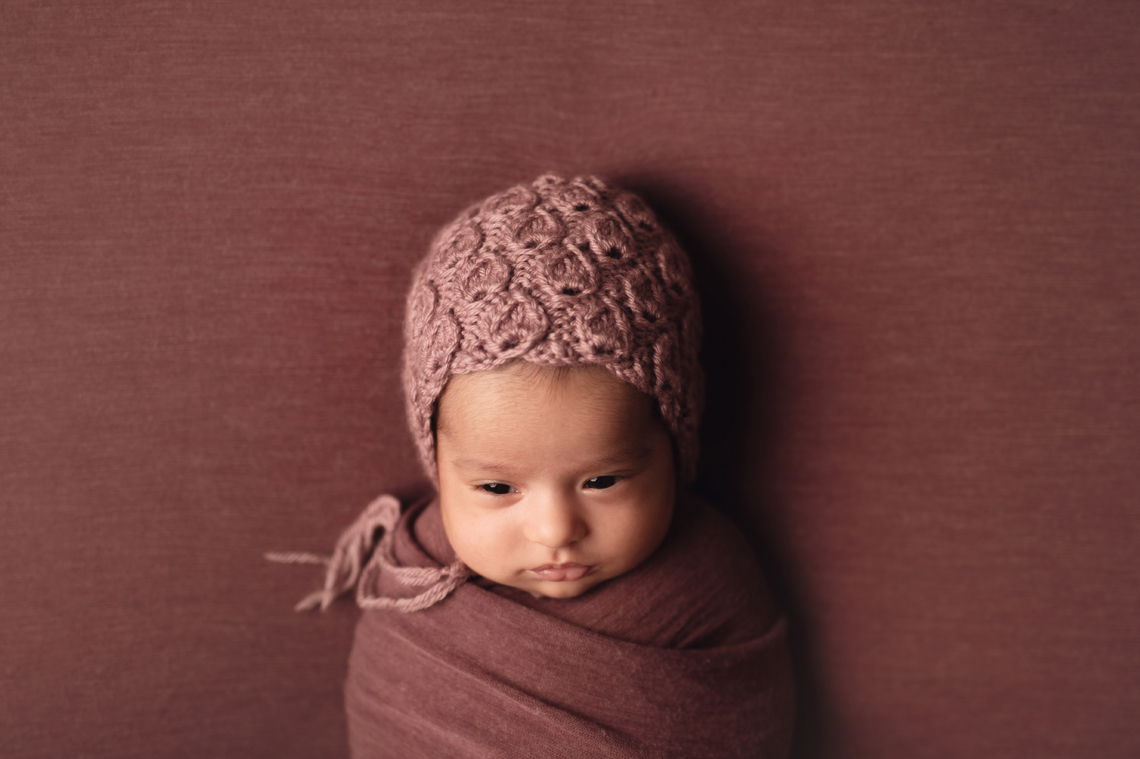 indian seven weeks old baby girl wrapped in fabric and wearing knitted hat